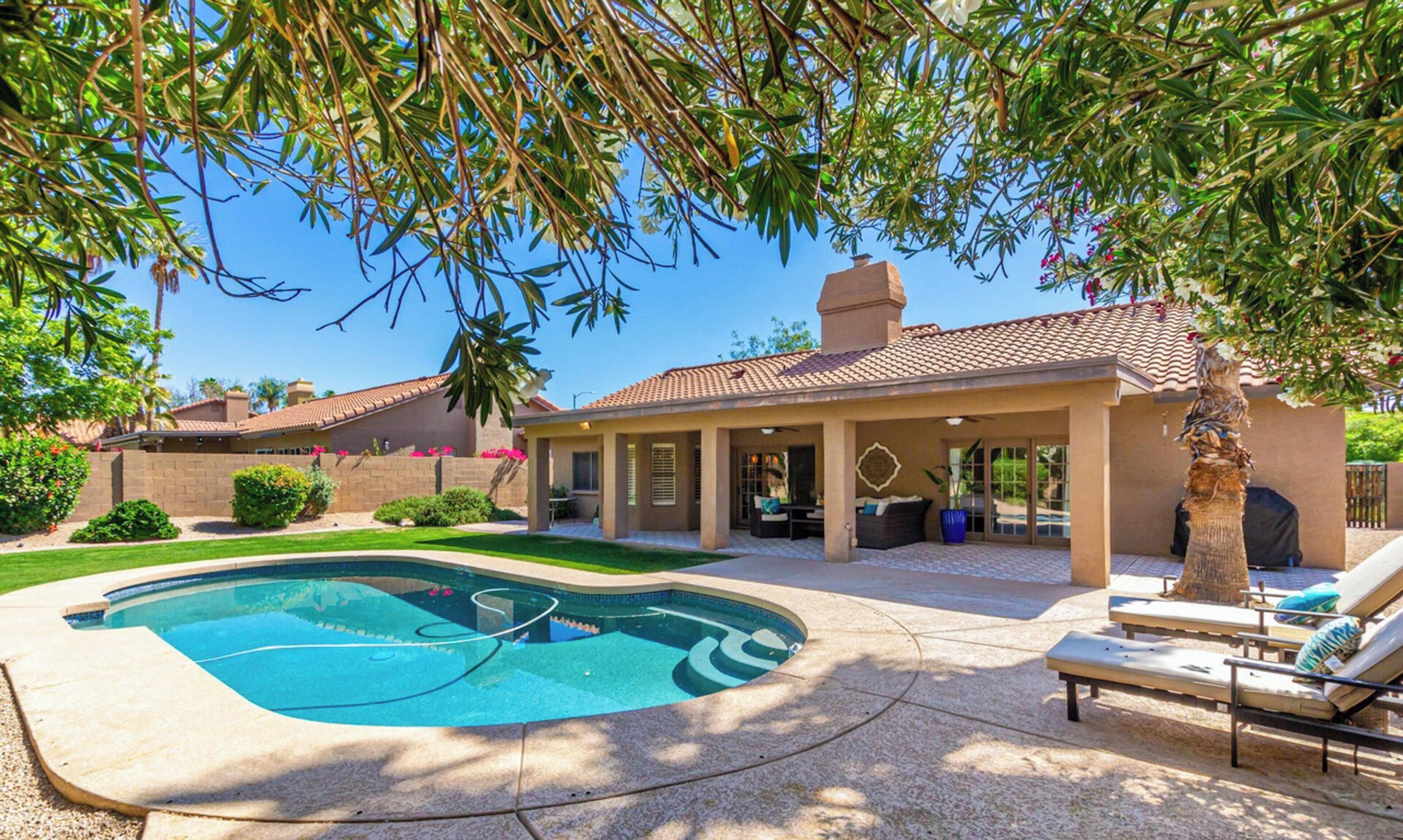 A residential property with a swimming pool, patio furniture, and a covered outdoor seating area.