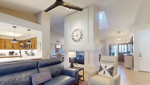 A spacious living room with a leather sofa, a cream-colored armchair, and a large wall clock. - Beautiful single-level home with enclosed yard, pool, patio & WiFi (Scottsdale)