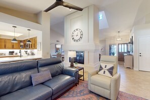 A spacious living room with a leather sofa, a cream-colored armchair, and a large wall clock. - Beautiful single-level home with enclosed yard, pool, patio & WiFi (Scottsdale)