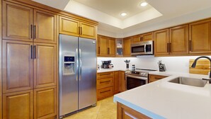 A modern kitchen with wooden cabinets, stainless steel appliances, and a large island with a sink. - Beautiful single-level home with enclosed yard, pool, patio & WiFi (Scottsdale)