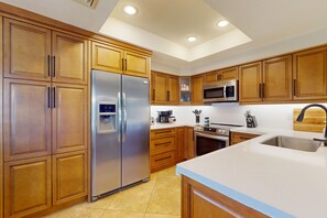 A modern kitchen with wooden cabinets, stainless steel appliances, and a large island with a sink. - Beautiful single-level home with enclosed yard, pool, patio & WiFi (Scottsdale)
