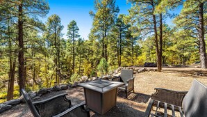 An outdoor seating area with a table and chairs, surrounded by a forest. - Wonderful dog-friendly home with hot tub, firepit, & washer/dryer (Lakeside)