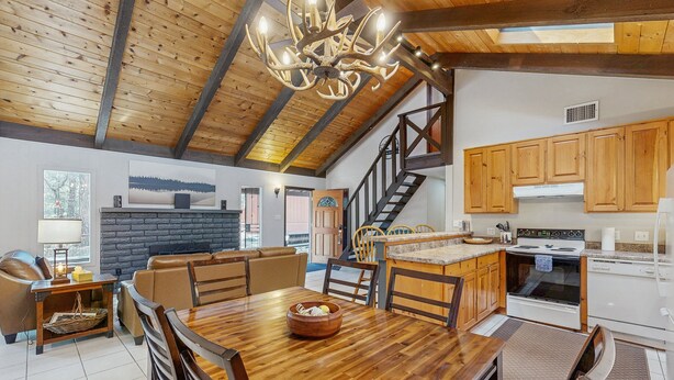 A spacious living area with a wooden dining table, a fireplace, and a large chandelier. - Wonderful dog-friendly home with hot tub, firepit, & washer/dryer (Lakeside)