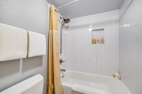 A bathroom with a bathtub, a showerhead, and a towel rack. - Convenient Old Town condo with pool, spa, gym, game room & balcony - near dining (Scottsdale)