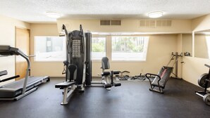 Et fitnesscenter med løbebånd, styrkemaskiner og en bænk.