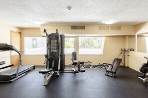 Une salle de sport équipée d’un tapis de course, d’appareils de musculation et d’un banc.