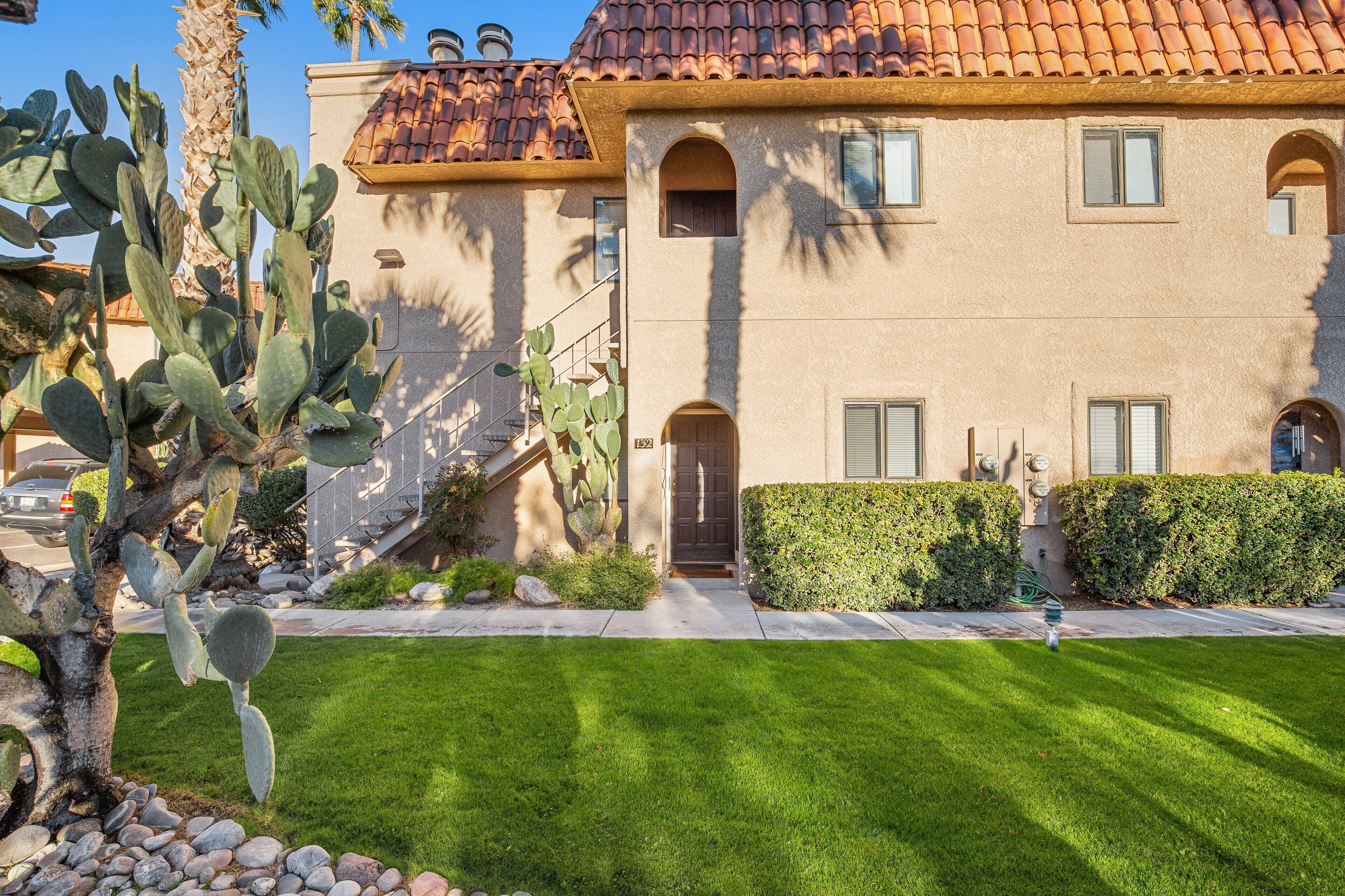 A two-story building with a tiled roof, a front door, and a well-maintained lawn.