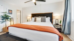A modern bedroom with a large bed, a ceiling fan, bedside lamps, and a potted plant. - Stylish Old Town Scottsdale condo with pool, spa, gym, & game room (Scottsdale)