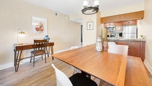 A modern kitchen with wooden cabinets, stainless steel appliances, and a dining area with a wooden table and chairs. - Stylish Old Town Scottsdale condo with pool, spa, gym, & game room (Scottsdale)