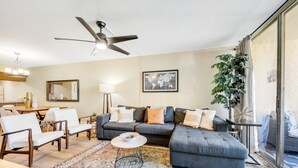 A living room with a grey sectional sofa, white armchairs, a coffee table, and a patterned rug. - Stylish Old Town Scottsdale condo with pool, spa, gym, & game room (Scottsdale)