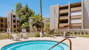A swimming pool with lounge chairs and a fence, surrounded by buildings and trees. - Stylish Old Town Scottsdale condo with pool, spa, gym, & game room (Scottsdale)