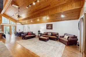 A spacious living room with wooden floors and ceiling, furnished with leather sofas and a large rug. - Spacious home with ping-pong, grill, patio, fast WiFi, & washer/dryer (Pinetop)