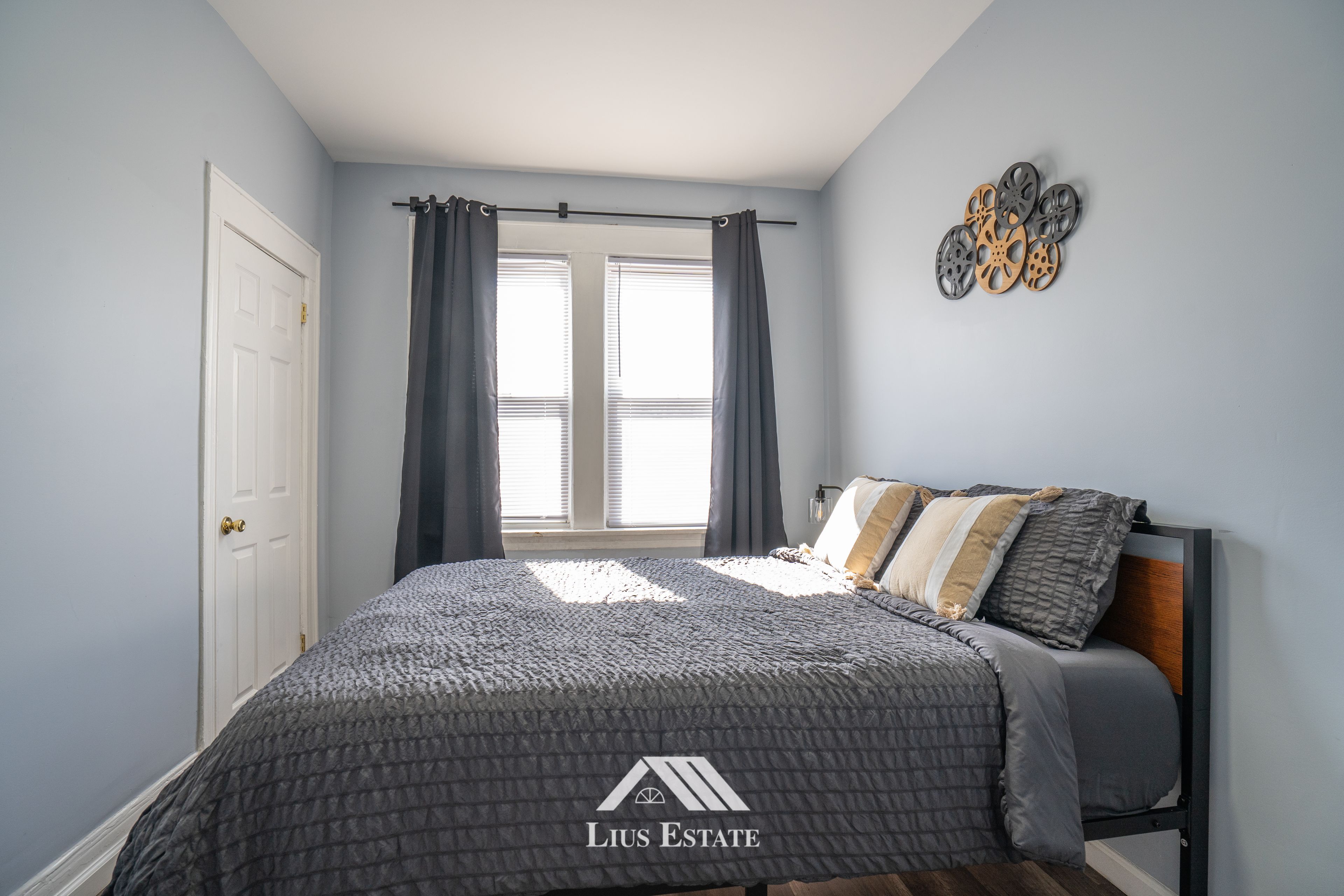 Une chambre à coucher avec un lit, des rideaux, une fenêtre et un élément de décoration fixé au mur.