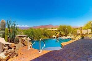 Un espace piscine offrant une vue sur les montagnes, entouré de cactus et de rochers.