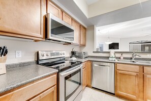 A modern kitchen with wooden cabinets, stainless steel appliances, a granite countertop, and a dishwasher. - Dog-friendly condo close to the city with central AC, shared pool, & hot tub (Scottsdale)