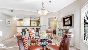 A dining area with a glass table and leather chairs, a kitchen in the background, and a framed picture on the wall. - Dog-friendly condo close to the city with central AC, shared pool, & hot tub (Scottsdale)