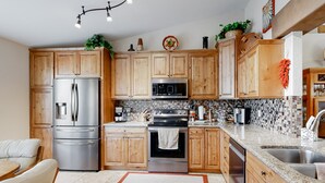 Una cocina moderna con armarios de madera, electrodomésticos de acero inoxidable y salpicadero de azulejos.