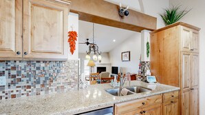 Una cocina con armarios de madera, encimera de granito y salpicadero con mosaicos.