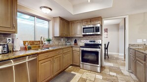A modern kitchen with wooden cabinets, stainless steel appliances, and a granite countertop. - Charming, dog-friendly home only minutes to Old Town with pool & custom bar (Scottsdale)