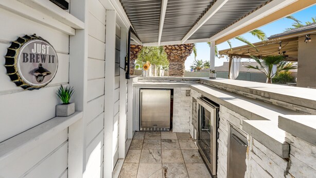 A modern kitchen with a stone wall, a built-in oven, and a stainless steel refrigerator. - Charming, dog-friendly home only minutes to Old Town with pool & custom bar (Scottsdale)