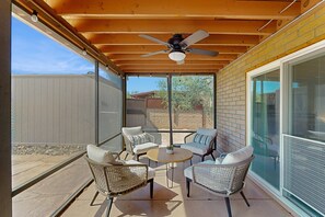 A covered patio area with wicker furniture, a ceiling fan, and a view of the backyard. - Dog-friendly modern stay with a heated private pool, sun room, & grill (Tucson)