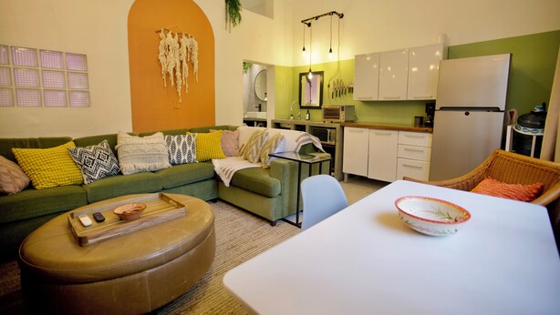 Un espace de vie compact comprenant un canapé vert, une table à manger et un coin cuisine.