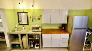 Une cuisine compacte équipée d’un évier, d’un four à micro-ondes, d’un grille-pain, d’un réfrigérateur et de placards.