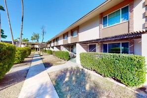 A hotel with a covered walkway, neatly trimmed hedges, and a clear blue sky. - 2-story dog-friendly condo with patio, outdoor pool, W/D, streaming, partial AC (Scottsdale)