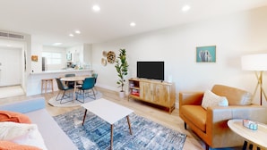A modern living room with a sofa, coffee table, and dining area. - 2-story dog-friendly condo with patio, outdoor pool, W/D, streaming, partial AC (Scottsdale)