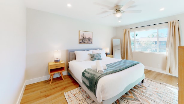 A bedroom with a bed, bedside tables, a ceiling fan, a window with curtains, and a rug. - 2-story dog-friendly condo with patio, outdoor pool, W/D, streaming, partial AC (Scottsdale)