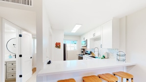 A modern kitchen with white cabinetry, a large island with bar stools, and a view to the dining area. - 2-story dog-friendly condo with patio, outdoor pool, W/D, streaming, partial AC (Scottsdale)