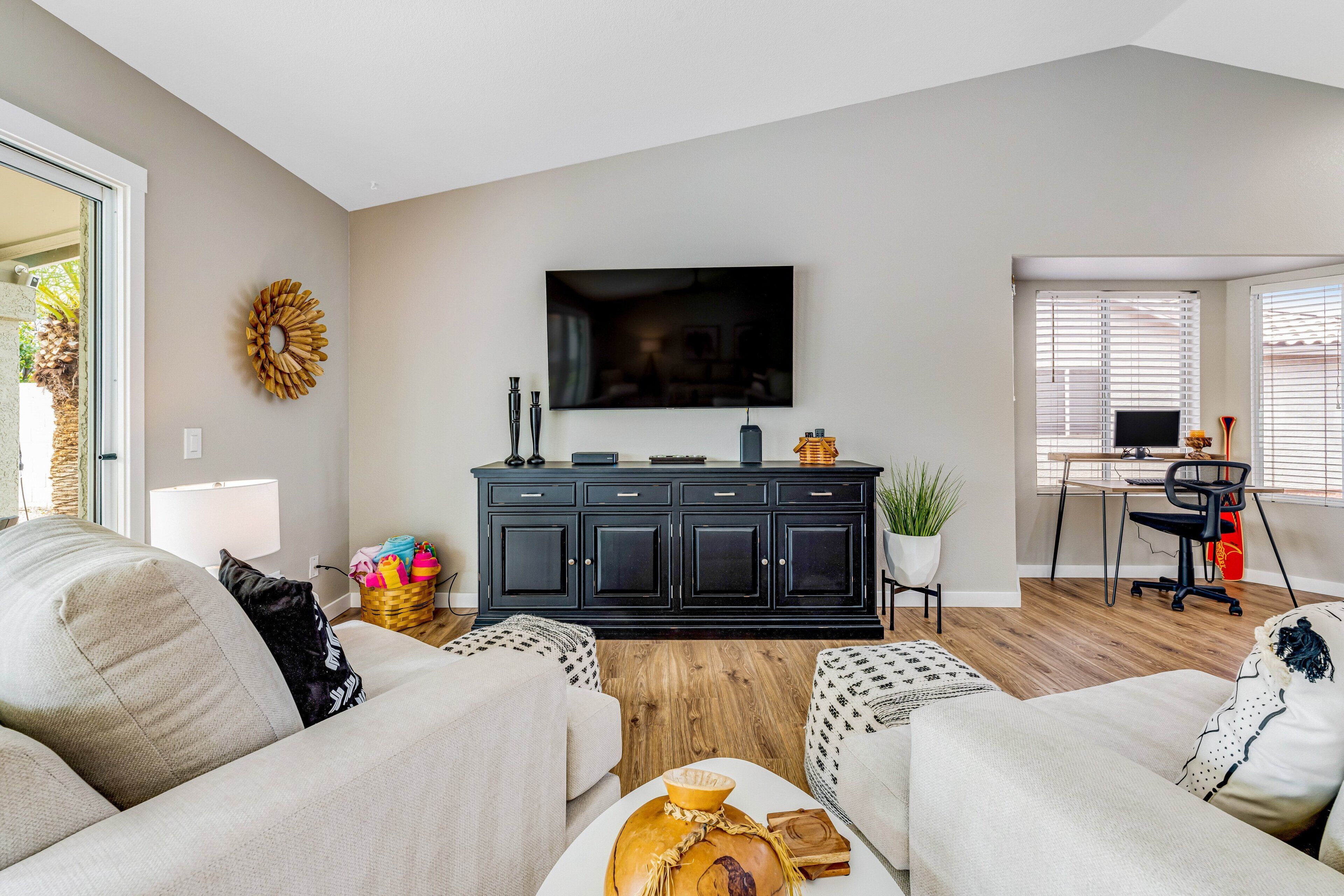A living room with a black entertainment unit, a flat-screen TV, and a dining area with a wooden table and chairs.
