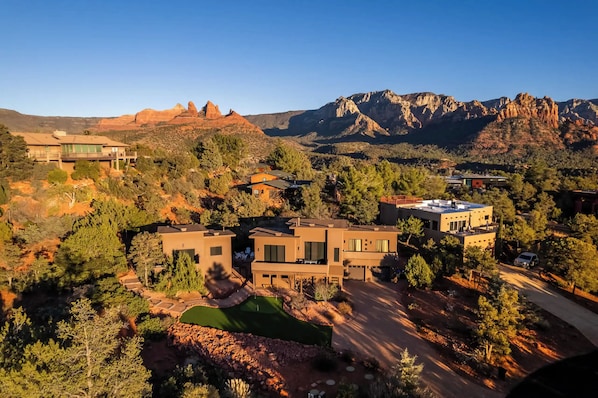 A modern residential area with multiple houses, a golf course, and red rock formations in the background. - Red Rock Retreat (Sedona)
