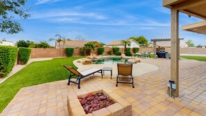 A backyard with a swimming pool, lounge chairs, a fire pit, and a pergola. - Peoria Paradise: Poolside Vibes & Family Good Times. Spacious Backyard with Pool (Peoria)