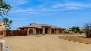 A residential house with a driveway, a fenced yard, and a clear blue sky. - Peoria Paradise: Poolside Vibes & Family Good Times. Spacious Backyard with Pool (Peoria)