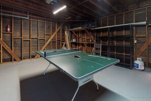 Una mesa de ping pong en una habitación con paredes de madera y suelo blanco.