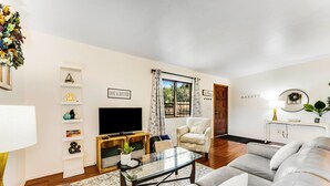 A modern living room with a sofa, TV, and decorative items. - Dog-friendly townhouse with enclosed patio, outdoor pool, mtn views, W/D, AC (Phoenix)