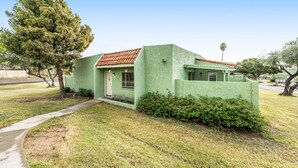 A single-story house with a green exterior, a red-tiled roof, and a front door. - Dog-friendly townhouse with enclosed patio, outdoor pool, mtn views, W/D, AC (Phoenix)