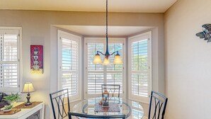 A dining area with a round glass table, black chairs, and a chandelier. - Inviting home with full kitchen, patio, central AC, & W/D (Sun City West)