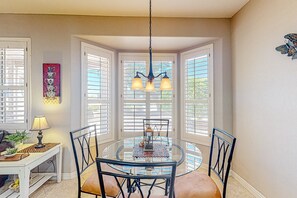 A dining area with a round glass table, black chairs, and a chandelier. - Inviting home with full kitchen, patio, central AC, & W/D (Sun City West)