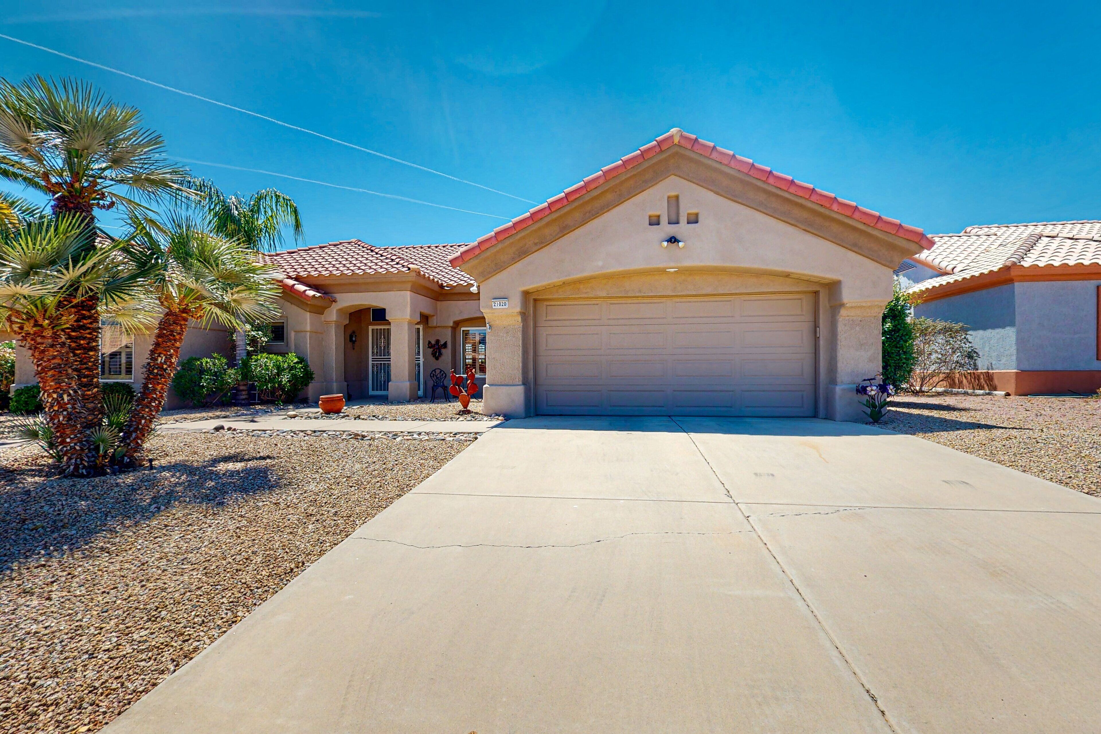 A single-story house with a red-tiled roof, a garage, and a driveway leading to the entrance.