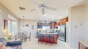 A spacious kitchen with a central island, wooden cabinets, and a stainless steel refrigerator. - Inviting home with full kitchen, patio, central AC, & W/D (Sun City West)