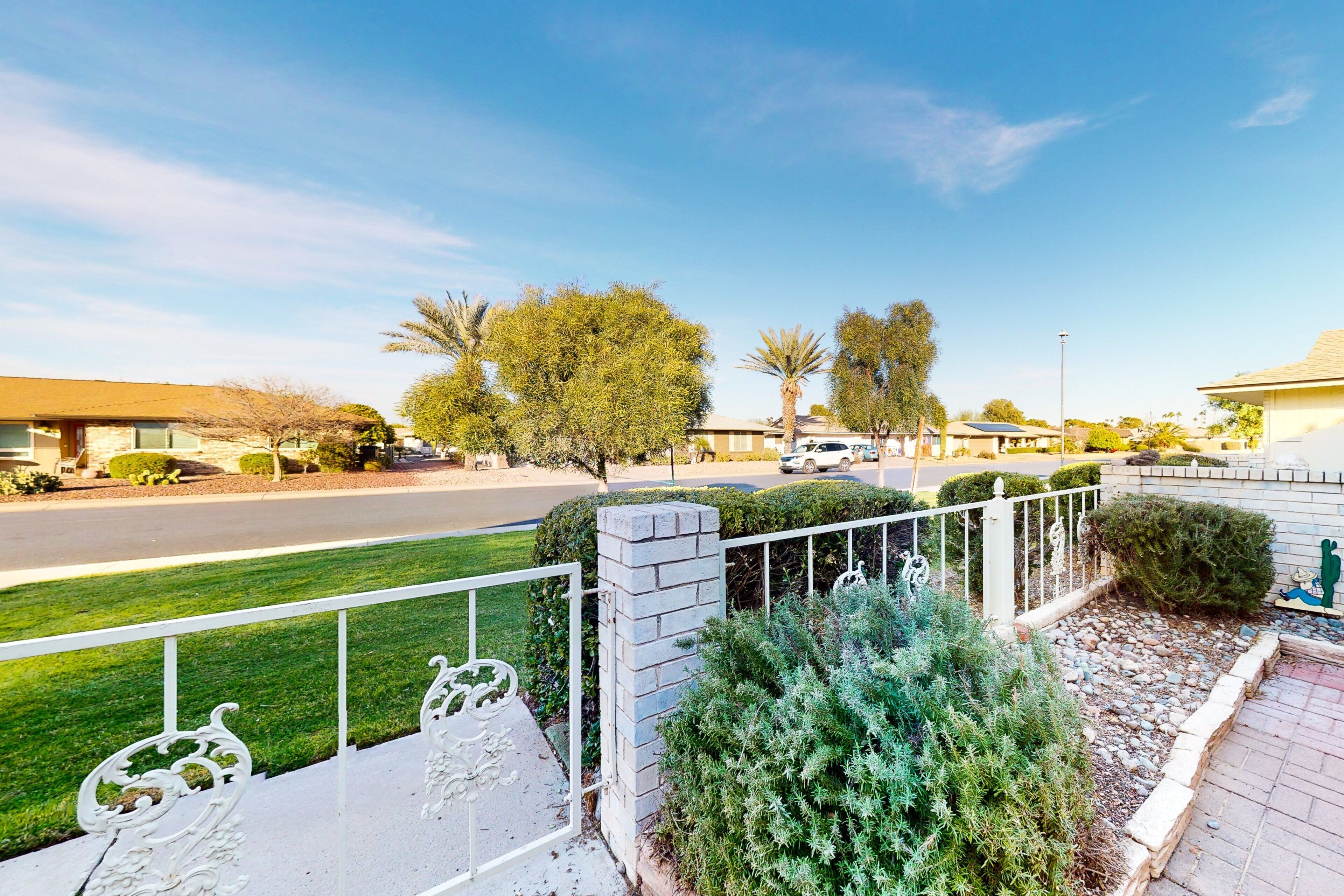 A residential street with houses, a clear sky, and a well-maintained lawn.
