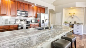 A kitchen with wooden cabinets, stainless steel appliances, a marble countertop, and a bull skull decoration. - Private desert dream home with enclosed yard, pool, furnished lanai, & grill (Mesa)