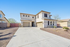 A two-story house with a garage, a driveway, and a small tree in the front yard. - Mountain-view gem - 2 large living rooms, heated pool, enclosed yard, AC & W/D (Avondale)
