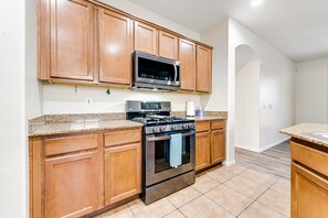 A kitchen with wooden cabinets, a stainless steel stove, and a microwave. - Mountain-view gem - 2 large living rooms, heated pool, enclosed yard, AC & W/D (Avondale)