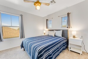 A bedroom with a bed, nightstands, a ceiling fan, and a window with curtains. - Mountain-view gem - 2 large living rooms, heated pool, enclosed yard, AC & W/D (Avondale)