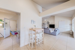 A spacious living area with a dining table and chairs, a sofa, and a television. - Charming home near walking paths with a work desk, grill, & patio - dog-friendly (Tempe)