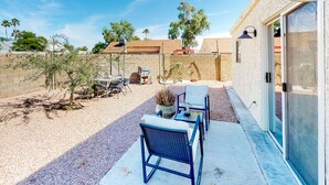 Un patio con mobiliario exterior, una mesita y una planta en maceta.