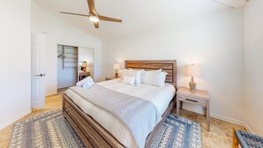 A bedroom with a wooden bed, a ceiling fan, bedside lamps, a patterned rug, and a walk-in closet. - Modern home with open layout, private pool, & washer/dryer - dog friendly (Phoenix)